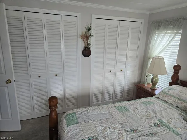 Carpeted bedroom featuring multiple closets and ornamental molding