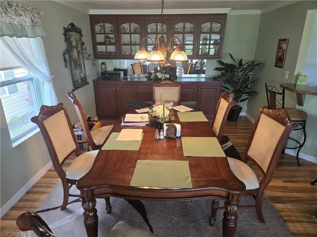 Dining room with crown molding, a notable chandelier, and dark hardwood / wood-style flooring