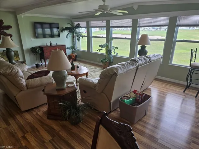 Living room with ornamental molding, plenty of natural light, hardwood / wood-style floors, and ceiling fan