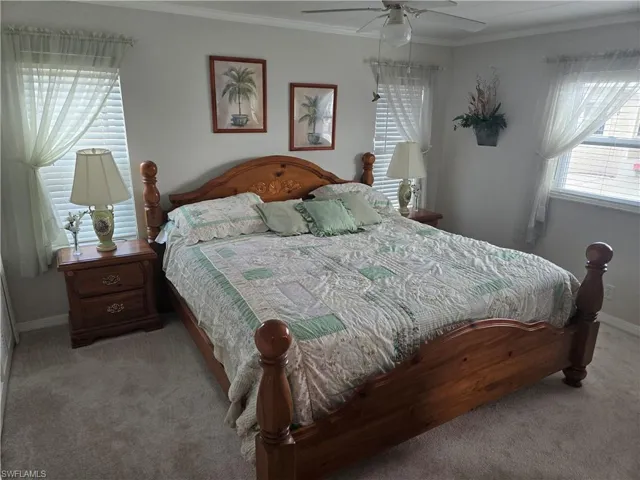 Bedroom with crown molding, light carpet, and ceiling fan
