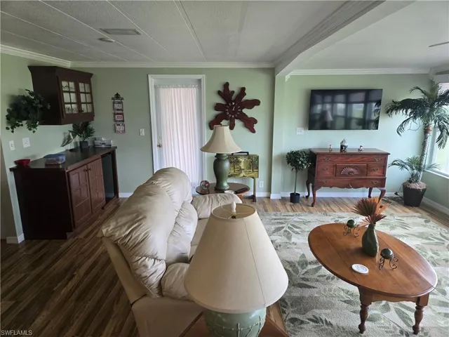 Living room with ornamental molding and dark hardwood / wood-style floors