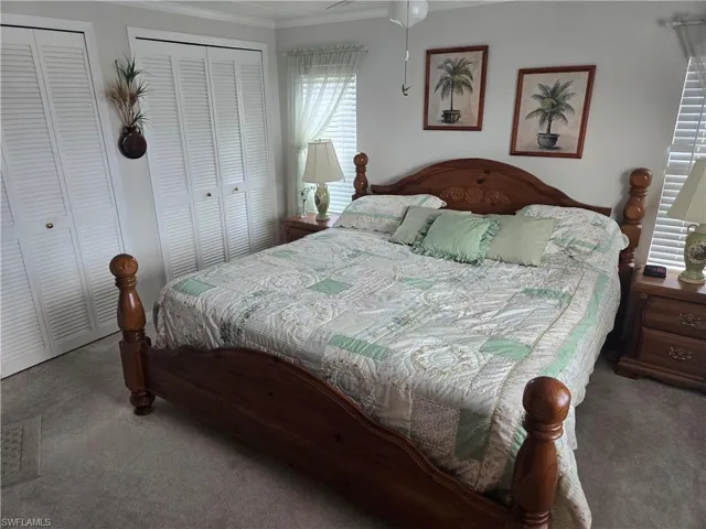 Carpeted bedroom featuring multiple closets and crown molding