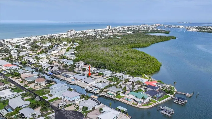 Aerial view of property and surrounding area featuring a nearby body of water and nearby suburban area