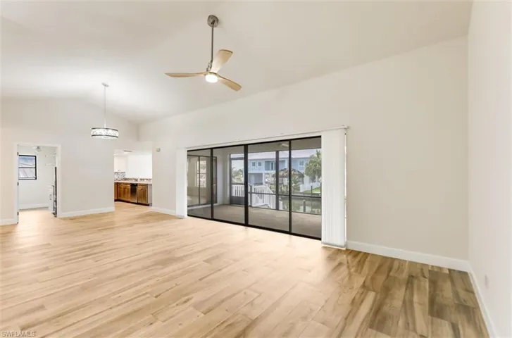 Empty room with light wood-type flooring, a ceiling fan, and high vaulted ceiling
