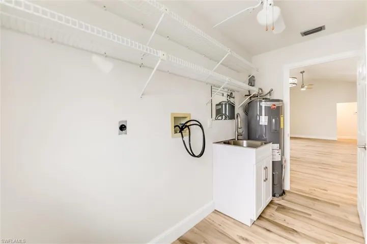 Laundry room featuring water heater, hookup for a washing machine, a ceiling fan, light wood finished floors, and electric dryer hookup