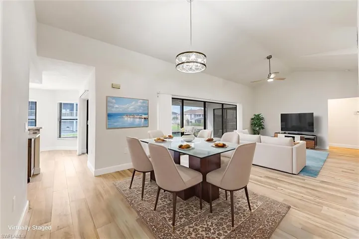 Dining area with light wood-style flooring, healthy amount of natural light, vaulted ceiling, a ceiling fan, and a chandelier