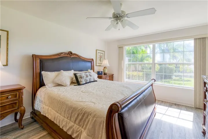 Spacious bedroom featuring light wood-finish flooring, a large window, and a ceiling fan