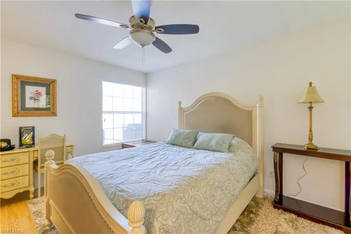 Light-filled room featuring a window with blinds, a ceiling fan with light fixture, and wood-finish flooring