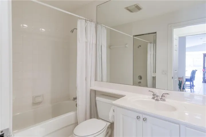 Bathroom featuring a white vanity with integrated sink, chrome faucet, and full-width mirror