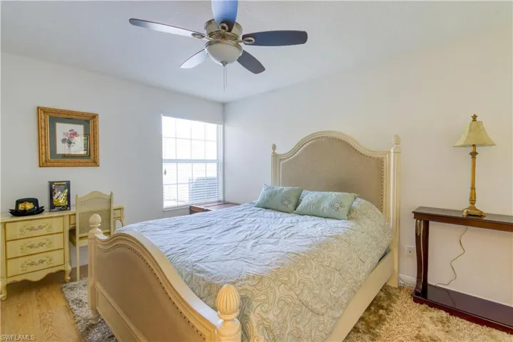 Bedroom featuring a ceiling fan, window with blinds, light wood-finish flooring, and white walls