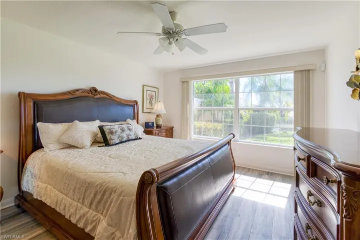 Expansive bedroom featuring large windows, wood-finish flooring, and a ceiling fan