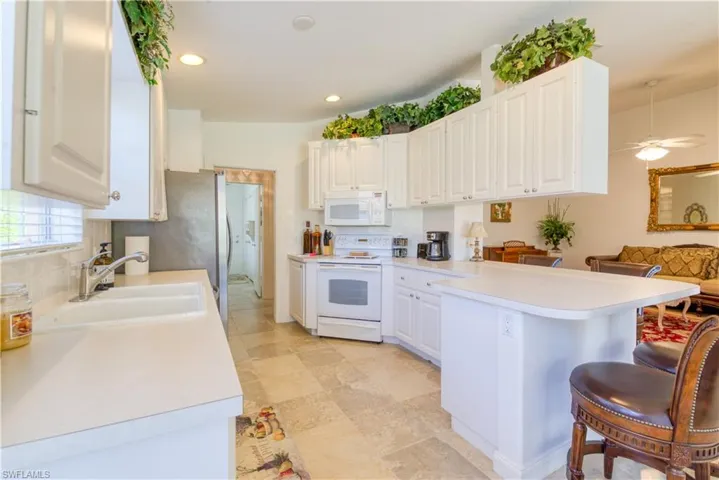 Bright kitchen featuring white cabinetry, light-toned countertops, a built-in double basin sink, and recessed lighting