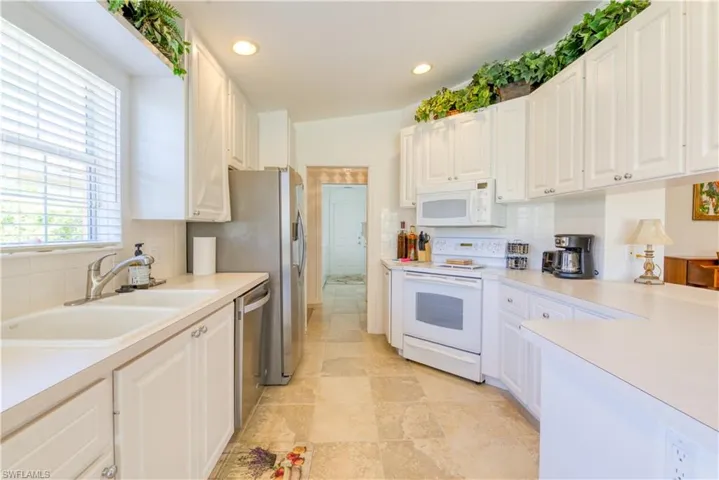 Kitchen featuring white cabinetry, light-toned countertops, a double basin sink, and stainless steel appliances