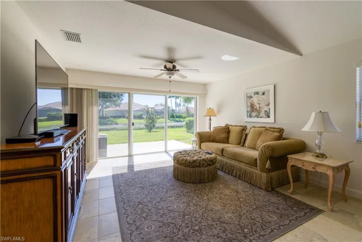 Spacious living area featuring large sliding glass doors, tile flooring, and a ceiling fan