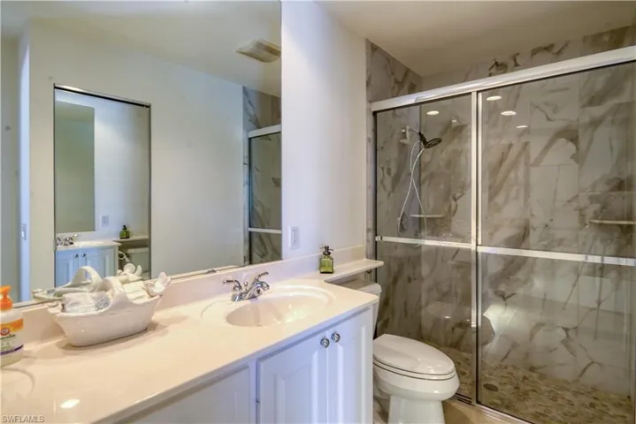Tiled shower with sliding glass doors and a handheld shower fixture