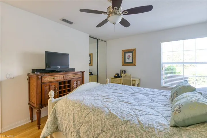 Neutral toned room featuring a ceiling fan with integrated lighting, wood-finish flooring, and a window with horizontal blinds