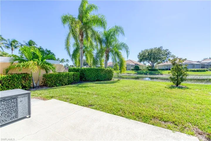 Expansive backyard featuring a manicured lawn, established tropical foliage, and mature palm trees