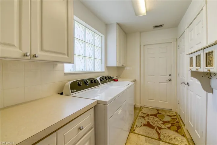 Dedicated laundry space featuring a glass block window, upper and lower cabinetry, counter space, and a utility sink