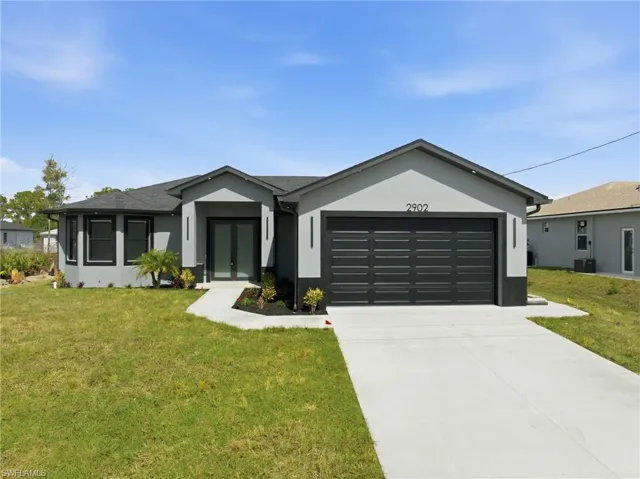 Ranch-style house featuring a front yard, a garage, stucco siding, and concrete driveway