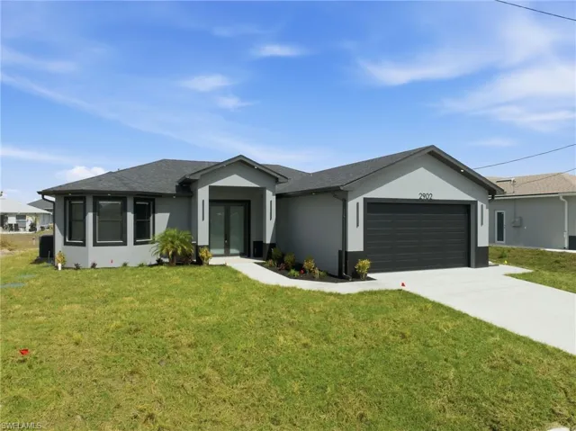 Single story home featuring a front yard, stucco siding, a garage, concrete driveway, and french doors