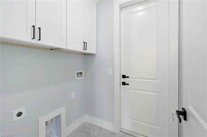 Laundry room featuring hookup for an electric dryer, cabinet space, washer hookup, and light marble finish flooring