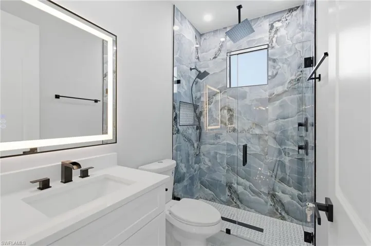 Bathroom featuring a marble finish shower and vanity