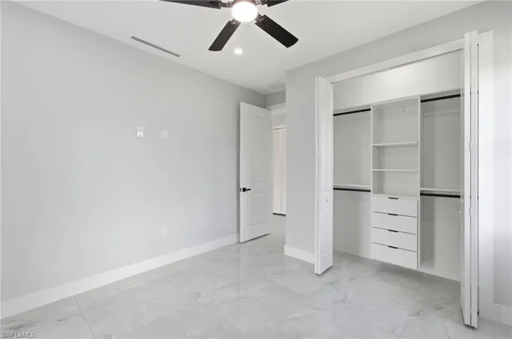 Unfurnished bedroom featuring a ceiling fan, a closet, light marble finish floors, and recessed lighting