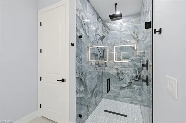 Full bath featuring a marble finish shower and baseboards