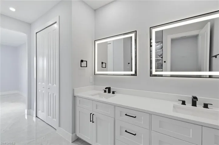 Bathroom featuring double vanity, light marble finish floors, a closet, and recessed lighting