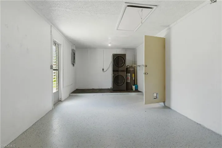 Utility space featuring a light-colored speckled floor coating, white walls, and a textured ceiling