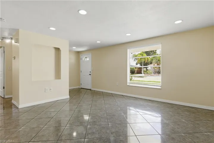 Spacious interior with neutral-toned walls, recessed lighting, and large format tile flooring