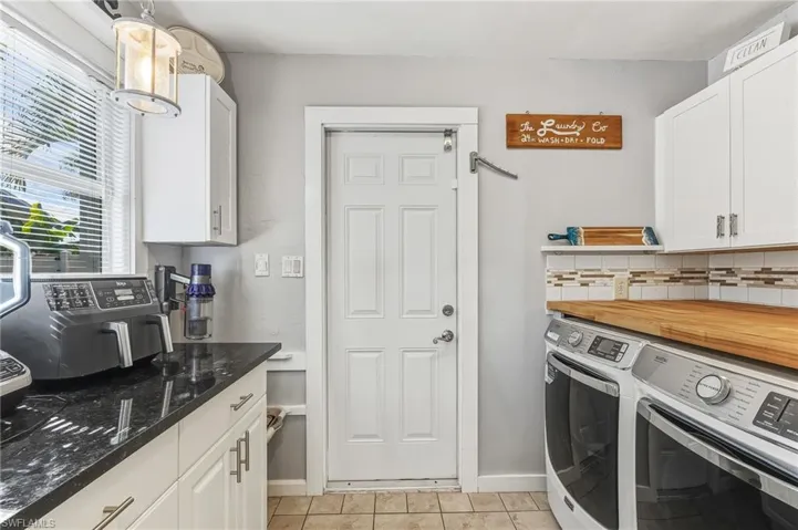 Kitchen featuring white cabinets, pendant lighting, washing machine and dryer, and backsplash
