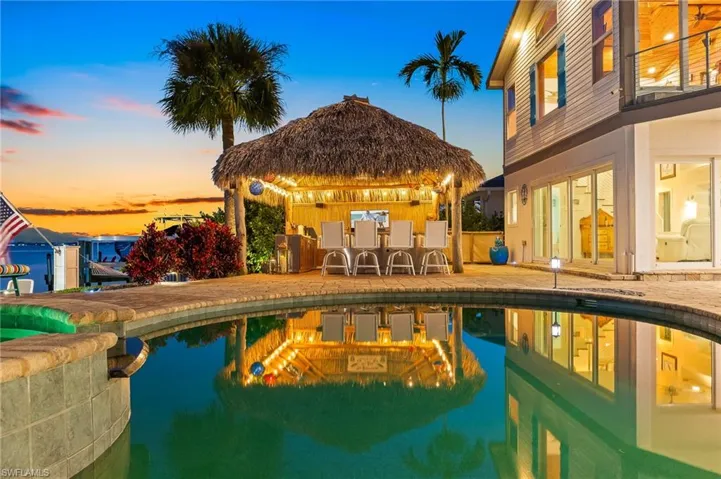 Pool at dusk featuring a patio area, a gazebo, and a pool with connected hot tub