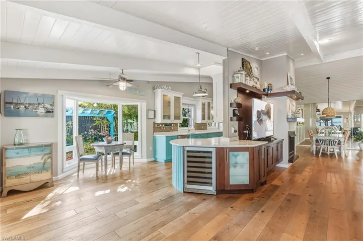 Kitchen with glass insert cabinets, decorative light fixtures, beverage cooler, wooden ceiling, and white cabinets