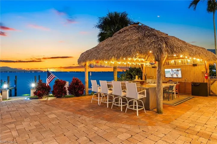 Patio terrace at dusk with a patio, a water view, and area for grilling