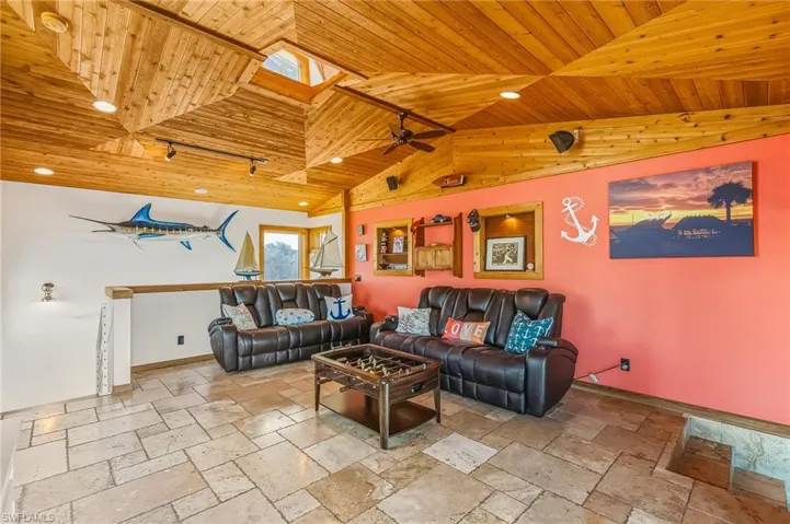 Living area with a skylight, wood ceiling, recessed lighting, stone tile floors, and ceiling fan