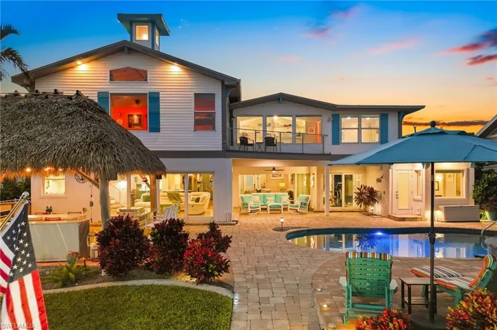 Back of house at dusk featuring outdoor lounge area, a balcony, a patio area, an outdoor pool, and ceiling fan