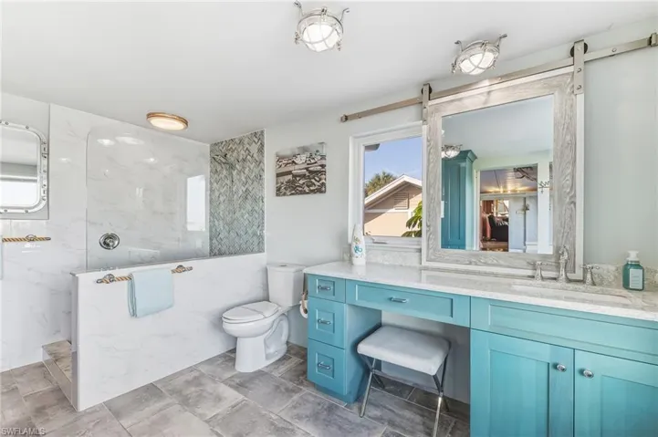 Bathroom featuring a marble finish shower and vanity