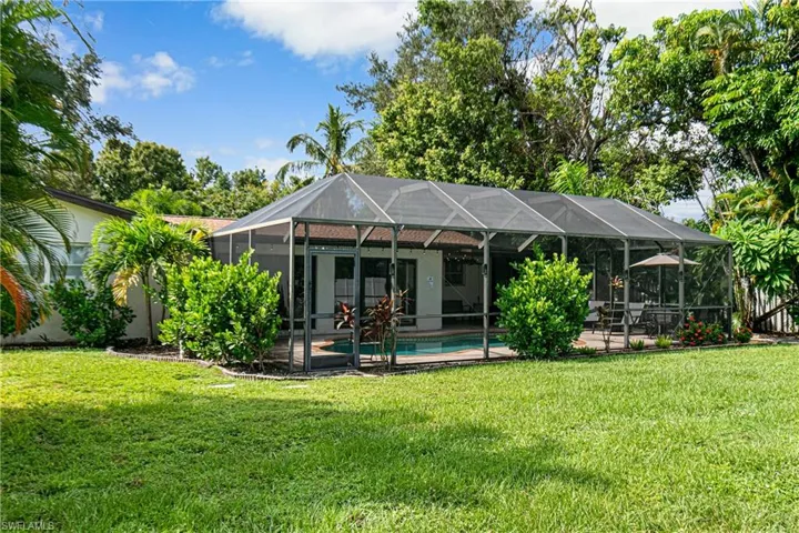 Back of house with a patio, a yard, and a lanai
