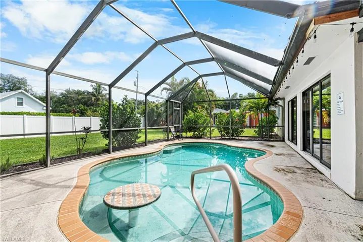 View of pool featuring glass enclosure and a patio