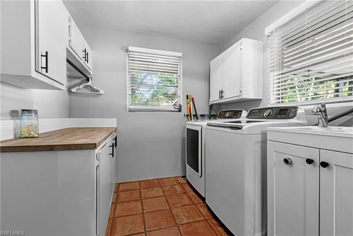 Clothes washing area featuring a healthy amount of sunlight, sink, independent washer and dryer, and cabinets