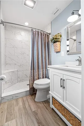 Bathroom featuring a shower with curtain, vanity, toilet, and hardwood / wood-style flooring
