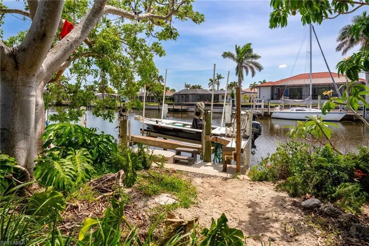 Dock featuring boat lift, a water view, and a residential view