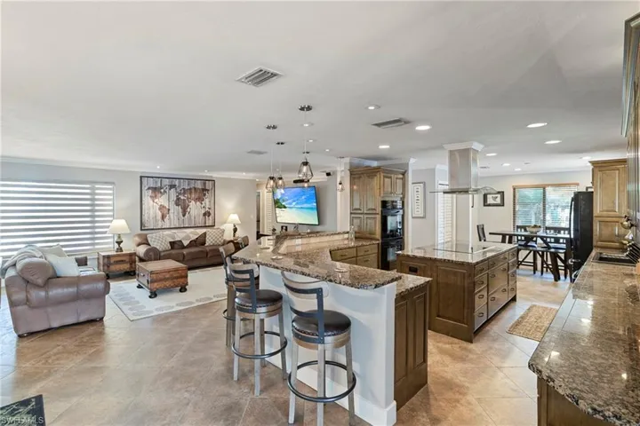 Kitchen with a kitchen island, crown molding, open floor plan, recessed lighting, and a kitchen breakfast bar