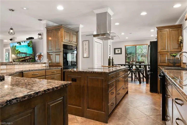 Kitchen featuring crown molding, a kitchen island, recessed lighting, island range hood, and dark stone counters