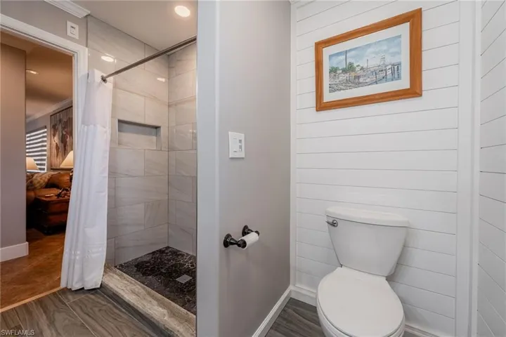 Full bathroom with a tile shower, wood finished floors, and crown molding