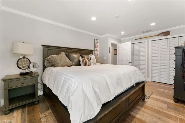 Bedroom featuring crown molding, wood finished floors, recessed lighting, and two closets