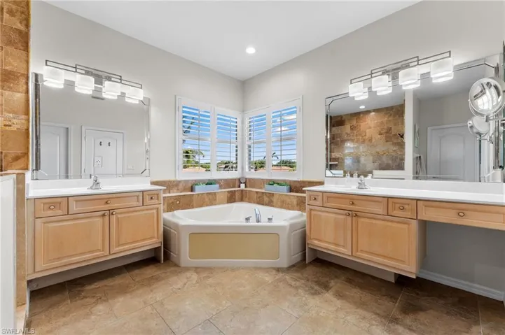 Corner tub, plantation shutters and updated lighting complete the primary bathroom. Vanity desk for makeup and additional seated chair.