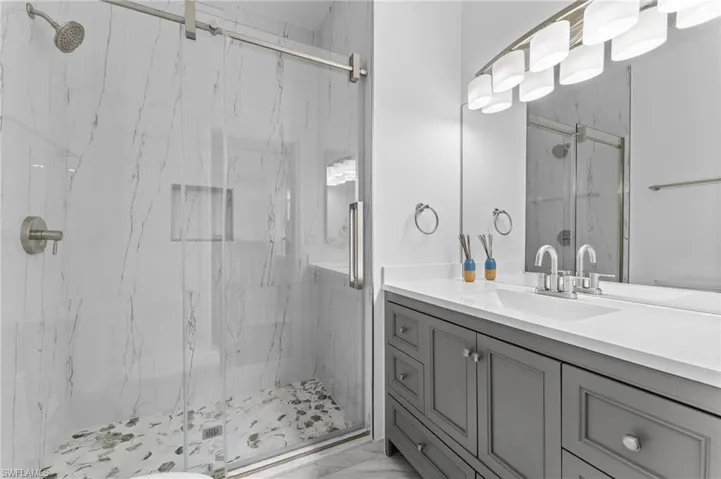 2024 Newly Updated Bathroom - large sink vanity, quartz countertops and porcelain tile shower with clear framed sliding doors and new lighting and plumbing faucets.