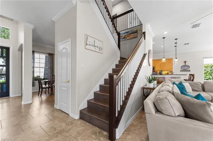Newly painted interior walls with crown molding and tile flooring, columned entry by dining room